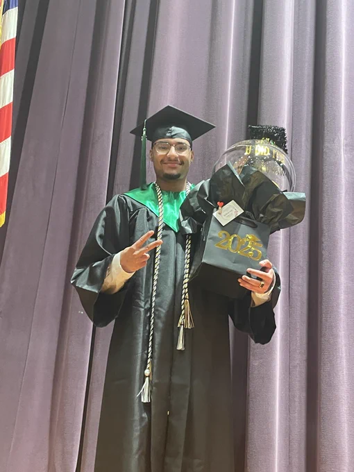 A graduate poses for a picture and smiles.
