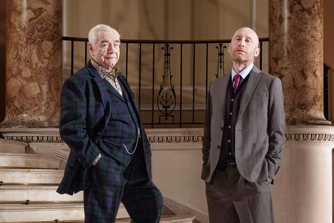 A photo showing two men in suits on an ornate staircase 