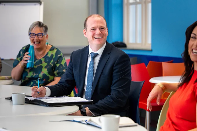 Minister Lyons writing and smiling.