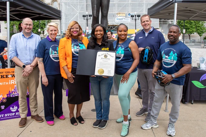 7 People in Blue Shirts smiling for a picture.