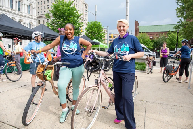 MTA Administrator Holly Arnold and Assistant MDOT Secretary Jawauna Greene stand holding their bikes.