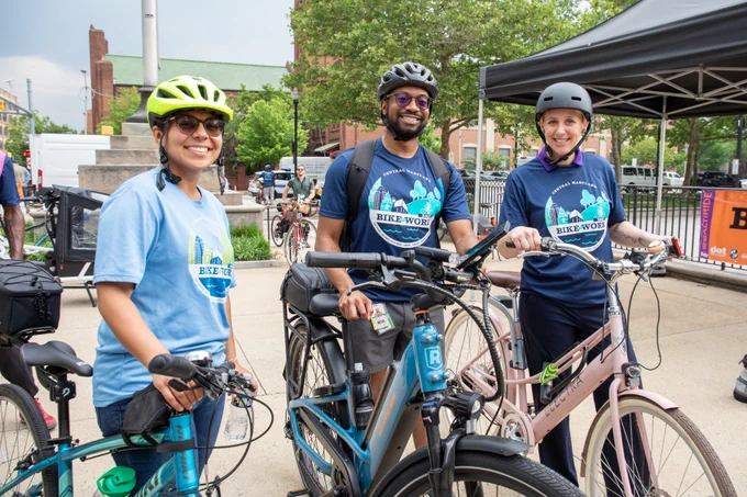 3 People smiling with bikes and helmets.
