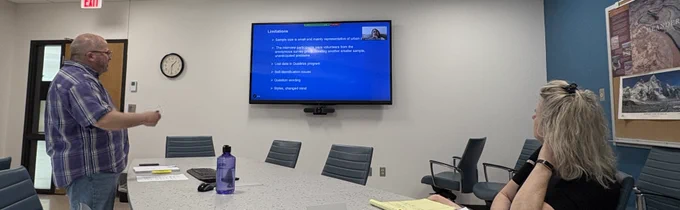person presenting and people in person and on Zoom listening