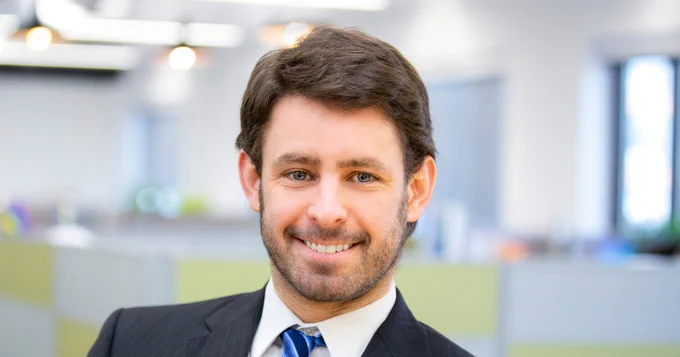 Ken Donald in a suit smiling in an office setting.