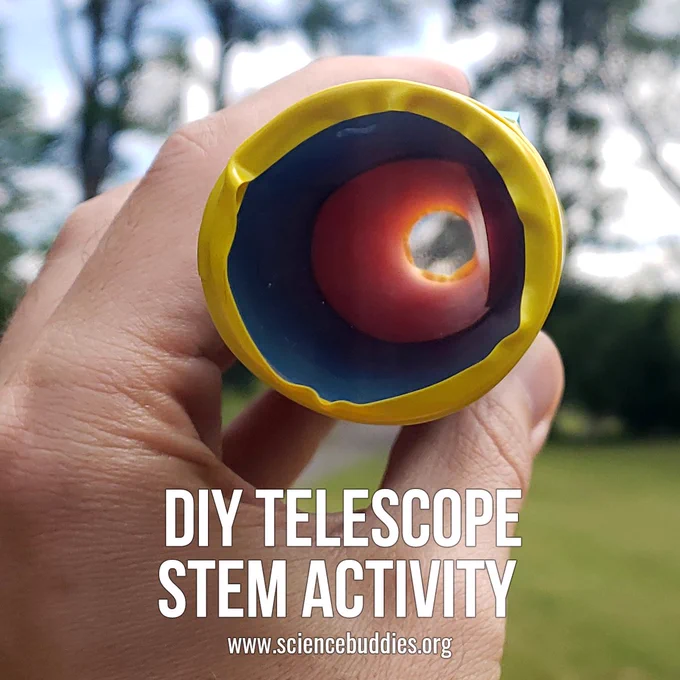 Hand holding a DIY telescope so that you can see through the lens to what is in the distance