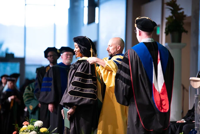 A faculty member places a doctoral hood on a doctoral graduate during a Commencement ceremony at the Lory Student Center.