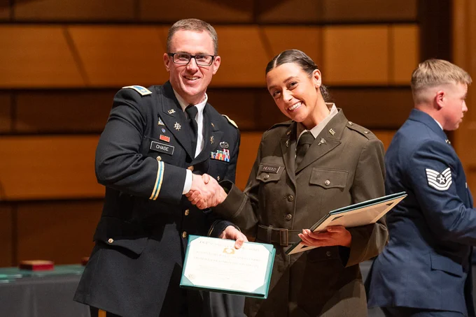 A military officer shakes hands with a ROTC cadet.