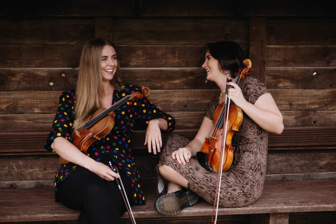 Lucia Mac Partlin and Maria Ryan holding their violins.