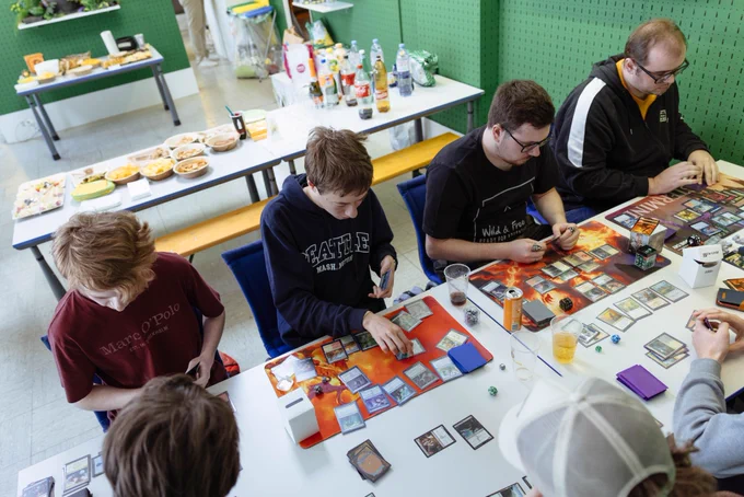 Overhead shot of Magic the Gathering players playing the game during the re-opening event in the "green section" of the CastleGames store in Oberburg, Switzerland. In the background the food area can be seen.