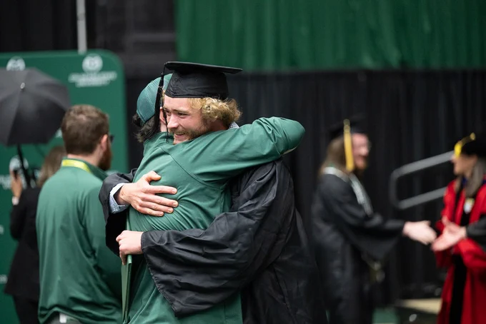 A graduating student hugging a supporter during a recognition ceremony at Moby Arena.