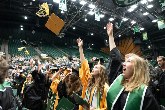 Graduating students throwing their graduation caps in the air during a recognition ceremony at Moby Arena.