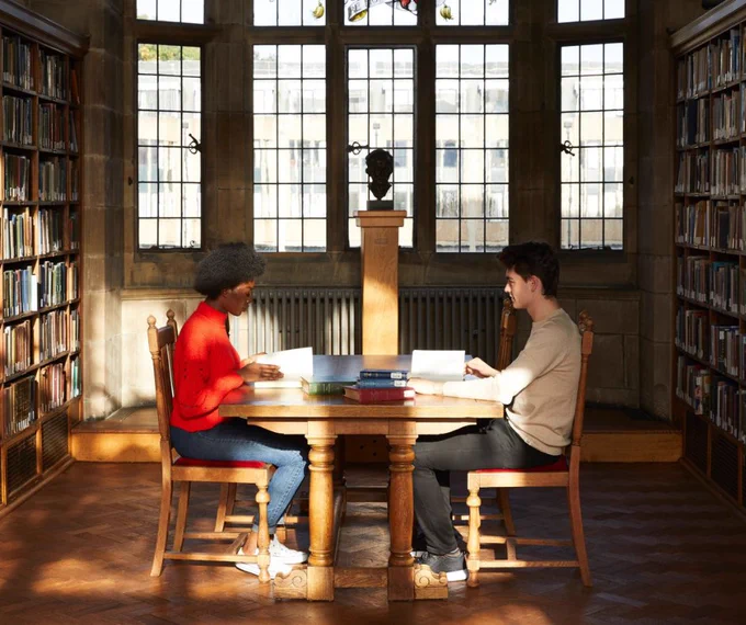 2 students studying in a library.