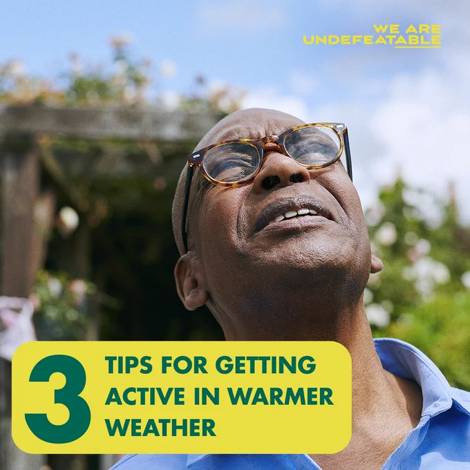 Person smiling upward while wearing glasses, under a sunny sky. Text overlay reads "3 Tips for getting active in warmer weather" from the "We Are Undefeatable" campaign.