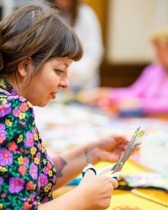 A workshop participant is cutting a piece of paper with scissors. 