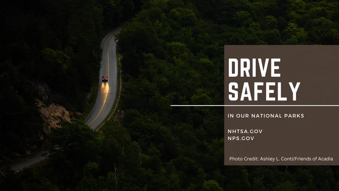 A red car drives down a wet, winding road at night. Text reads "Drive Safely in our National Parks. nhtsa.gov. NPS.gov. Photo Credit Ashley L. Conti/Friends of Acadia.