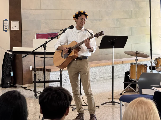 Louis Mendez playing guitar and sings as part of the program 