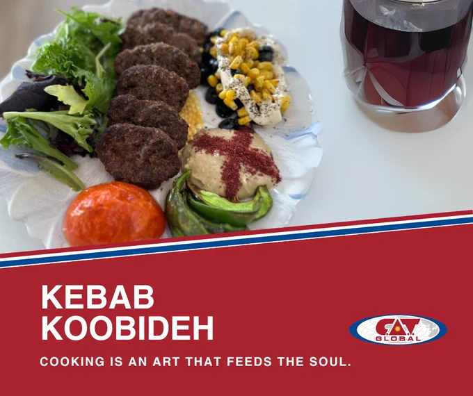 A decorative plate featuring five pieces of Kebab Koobideh served with mixed greens, a roasted tomato, hummus sprinkled with red seasoning, and a salad of corn, black beans, and tahini. 