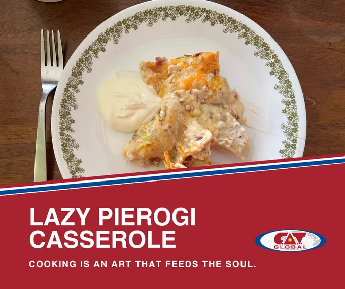 A serving of Lazy Pierogi Casserole topped with melted cheese and accompanied by a scoop of sour cream, presented on a white plate with a green floral border. A fork rests beside the plate on a wooden table. The design includes the CAT Global logo and the text “Lazy Pierogi Casserole.”