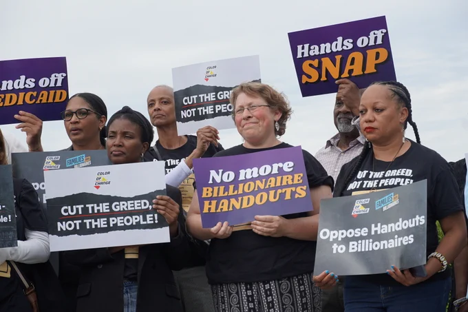 Color of Change leaders and advocates hold signs at a press conference. 
