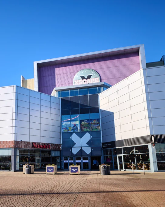 Exterior view of the Xscape entertainment complex featuring prominent signage, under a clear blue sky.