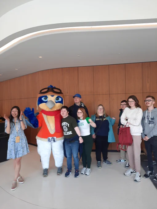 A large colourful AerCap mascot - Captain Aer is standing with a group of TCPID students. 