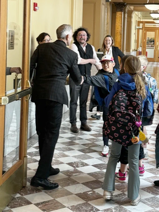 Photo of Mayor Wilson shaking hands with a young person at City Hall from Forest Park Elementary School during a tour organized by Urban Tour Group
