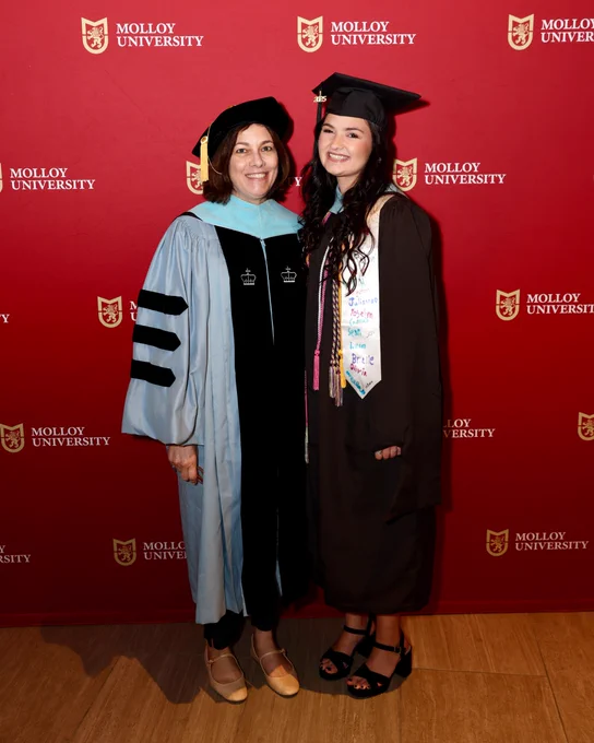 Two women in graduation attire with gowns and caps at Molloy University commencement