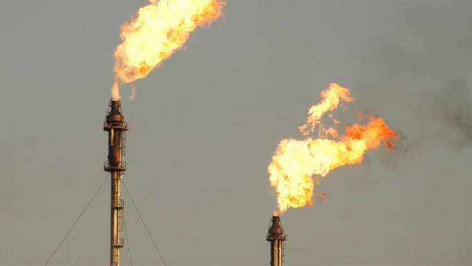 Large flames are pictured burning from two flare stacks during gas flaring.