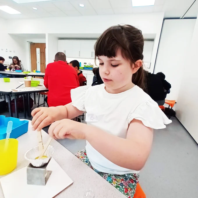 Child melting beeswax to make balms in the workshop 