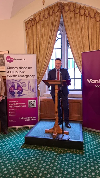 Wes Streeting standing at a lectern in a Parliament room, with a Kidney Research UK banner to his side. 