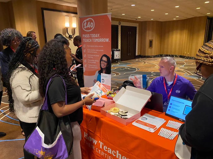 Guests visit exhibitor booth, 240 Tutoring. 