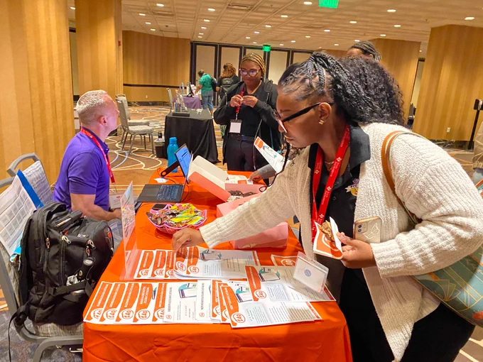 Guests visit exhibitor booth, 240 Tutoring. 