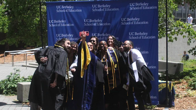 eight people from the principal leadership institute standing in front of the u c berkeley school of education backdrop bunched together for a selfie