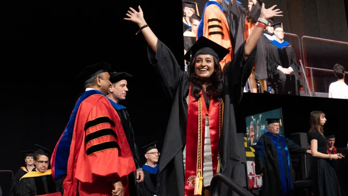 Graduate raising her hands in the air at the 2024 Undergraduate Commencement Ceremony after walking the stage