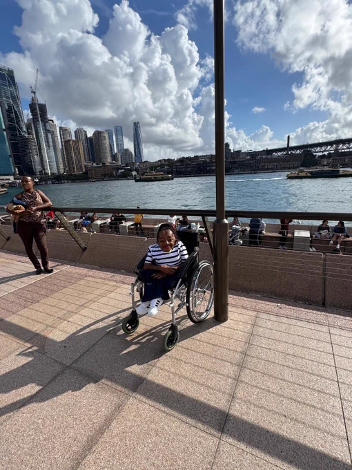 Australia Awards scholar, Florence, seated in her wheelchair with the Sydney cityscape in the background