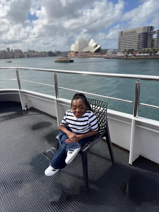 Australia Awards scholar, Florence, seated in a chair with the Sydney Opera House behind her.