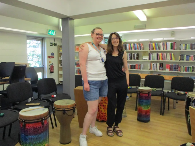 Two women standing in front of a drum circle