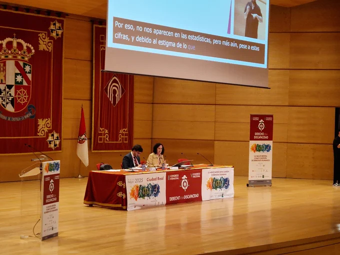 Imagen de la ponente junto al moderador en la mesa durante su intervención. 
