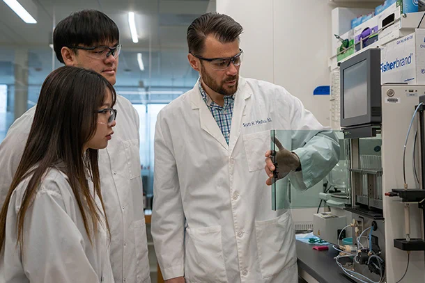 Three people work with lab equipment