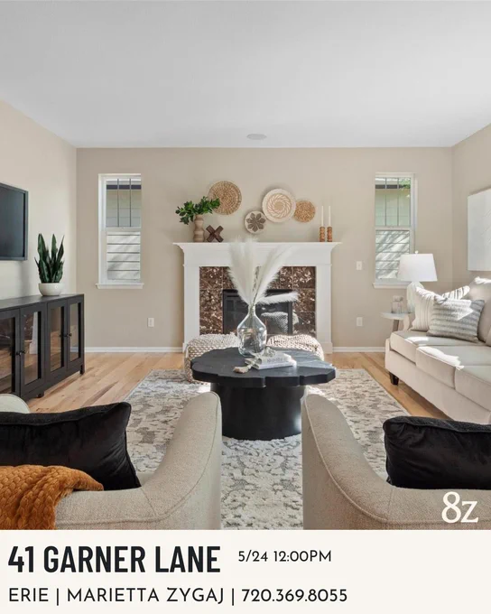 Interior of a stylish living room at 41 Garner Lane, Erie, decorated with a neutral palette featuring a sofa, chairs, a coffee table, and fireplace. An open house sign with agent Marietta Zygaj's contact information is displayed.
