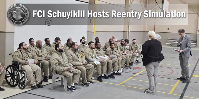 A group of individuals seated in a gym at FCI Schuylkill listening to a speaker during a Reentry Simulation event.