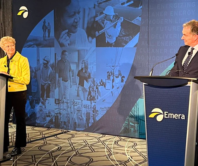Karen Sheriff, left, and Scott Balfour, right, look at each other with smiles as they stand at podiums featuring the Emera logo—a backdrop features various images of people and scenes related to energy and technology.