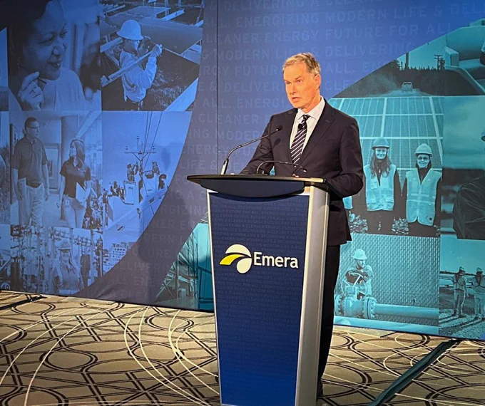 Scott Balfour is speaking at a podium with the Emera logo. The backdrop features various images of people and energy infrastructure.