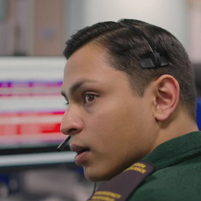 Liam sitting in front of control room screens at our Newham contact centre.