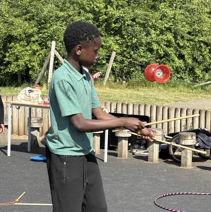 A school pupil playing with a diabolo juggling toy. Disgybl ysgol yn chwarae gyda thegan jyglo diabolo.