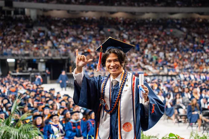 Graduate in cap and gown smiling at a vibrant UTSA Commencement ceremony.