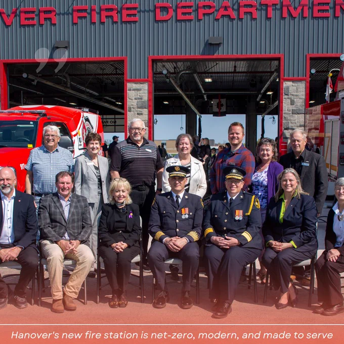 Group of individuals standing in front of the new Hanover Fire Department fire station with a fire truck visible in the background.