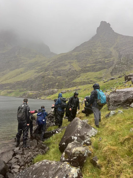 Group of bryologists in the rain with mountains and lake in the background