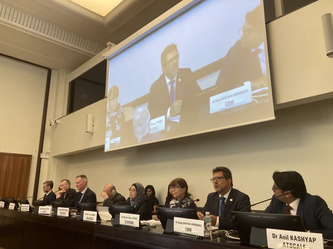 Dr. Diego Santana-Hernández of CBM speaks on a panel at the WHA78 side-event titled “Eye Health Has 2030 in Sight,” held at the United Nations in Geneva. He is seated among fellow panellists from international organisations and governments, including representatives from Slovenia, Malaysia, Paraguay, and ATscale. A large screen above the panel displays a close-up of Dr. Santana-Hernández as he speaks.