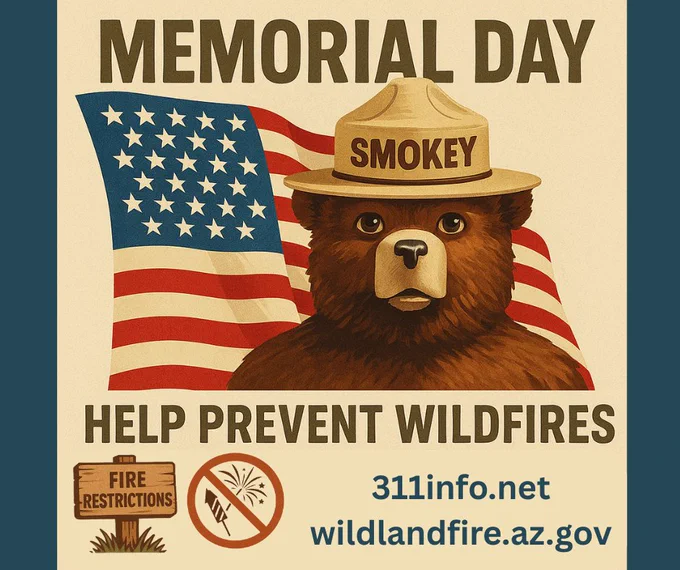 Poster featuring Smokey Bear wearing a ranger hat labeled "Smokey," with an American flag in the background. The top text reads “Memorial Day.” Below Smokey, bold text says “Help Prevent Wildfires.” Icons at the bottom show a wooden sign that says “Fire Restrictions” and a “No Fireworks” symbol. Website links “311info.net” and “wildlandfire.az.gov” appear beneath the icons.